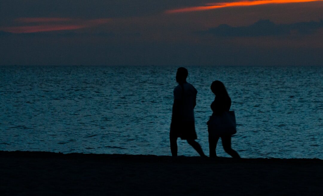 couple walking on beach at sunset